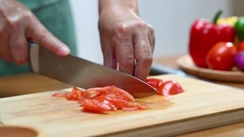 Closeup of hands slicing tomato with a sharp knife on wooden board in kitch.. Stock Footage 312978974