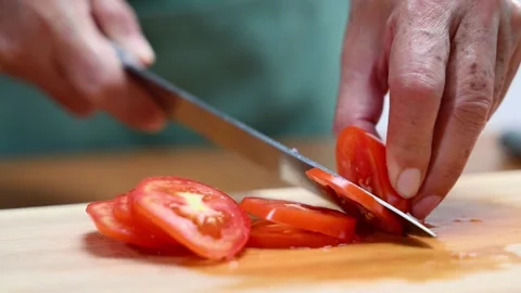 Closeup of hands slicing tomato with a sharp knife on wooden board in kitch.. Video stock 312979020