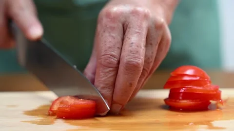 Closeup of hands slicing tomato with a sharp knife on wooden board in kitch.. Video stock 312979038