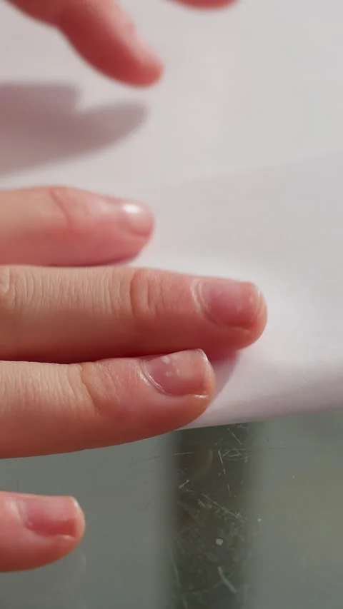 Closeup hands smoothing paper edge on glass table, tiny moisture on fingertips Video stock 329406038