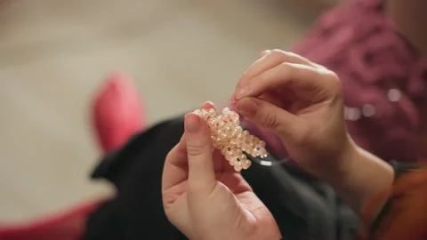 Closeup hands threading beads into bracelet, careful artisan process assembling Stock-Footage 346560166