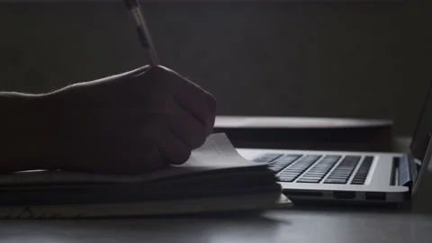 Closeup, hands turn the page write and make notes in diary. Laptop lays on table Stock Footage 152168913