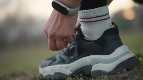 Closeup Hands Tying Black Sneaker Laces On Grass, Striped Socks And Watch Stock Footage 329538439
