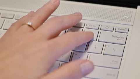 Closeup of hands typing on laptop keyboard with gold ring in soft lighting Stock Footage 316733739