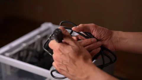 Closeup hands of unrecognizable man carefully holding and uncoiling black power Stock Footage 287511831