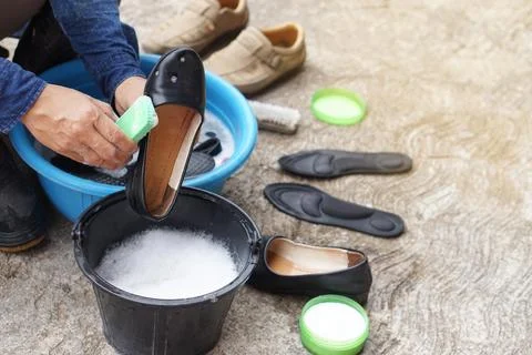 Closeup hands use brush to clean and wash black shoes Stock Photos