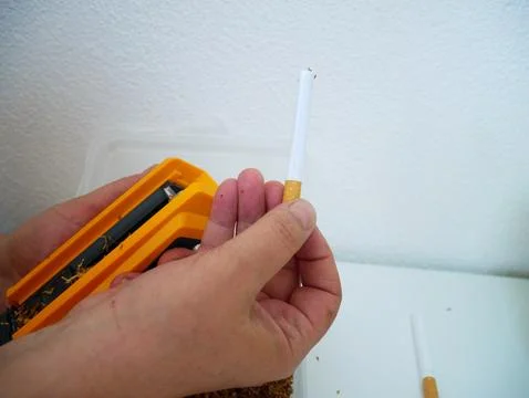 Closeup of hands using a yellow cigarette injector machine to fill a filter tube Stock Photos