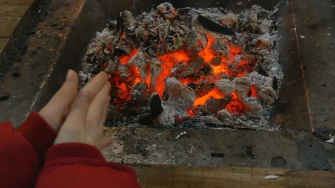 Closeup hands warming up at smoldering coal Stockbeeldmateriaal 100705890