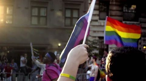 Closeup on hands waving rainbow flags for LGBT Gay Pride March in NYC Stock Footage