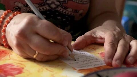 Closeup of hands writing a shopping list with a pencil on a small paper not.. Stock Footage 340917200