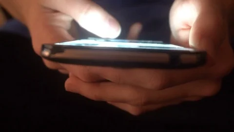 Closeup of hands of a young man flipping through the news on the smartphone Stock Footage 83622368