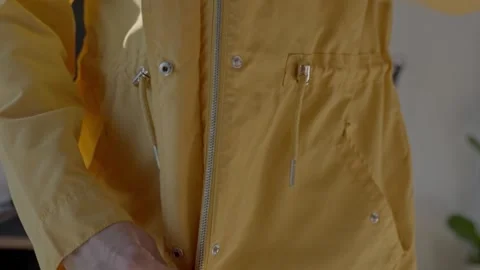 Closeup of hands zipping yellow jacket over black top and light denim jeans Stock Footage 330133679