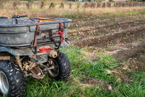 Closeup of hauling bin strapped to a farm ATV by a new garden Foto stock