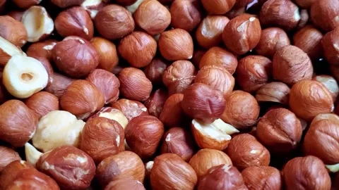 Closeup of hazelnuts dropping on top of a pile of more hazelnuts with Stock Footage 140935020