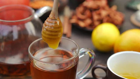 Closeup high angle view placing golden honey in green tea outdoors. Female Video stock 237512186