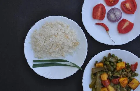 Closeup high angle view of rice, matar paneer mix veg and salad on white plate Stock Photos