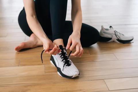 Closeup high angle view of unrecognizable athletic female tying shoelaces on Stock Photos