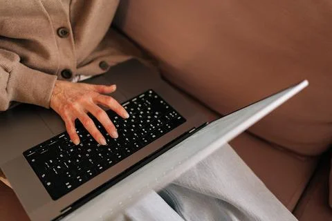 Closeup high-angle view of unrecognizable middle-aged woman using laptop, typing Stock-Fotos