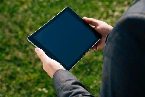 Closeup to hold the tablet in the hands of a man against a background of gree Stock Photos