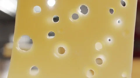 Closeup of hole in slice of cheese. Slow motion video Stock Footage 120456333
