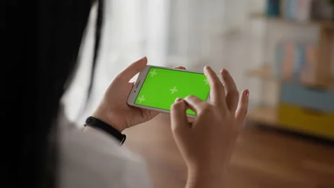 Closeup horizontal of hand woman using smartphone with green screen while lying Stockbeeldmateriaal 202154471
