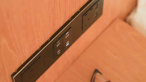 Closeup hotel headboard outlet panel showing warm wood grain, empty sockets and Stock Footage 330040193