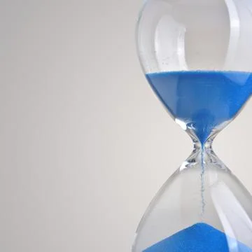 Closeup hourglass on gray background Stock Photos