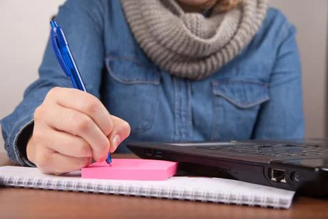 Closeup of human taking notes on papers while working on the computer 스톡 사진