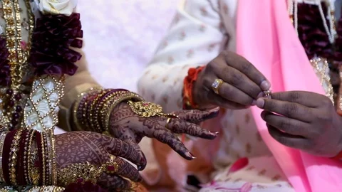 Closeup of a husband putting a ring on his wifes finger at an Indian wedding Видео 123550445