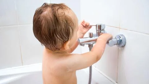 Closeup image of 1 year old boy opens water faucet in bathroom Stock Photos