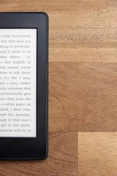 Closeup image of an electronic reader with text on the screen on a wooden desk Stock Photos