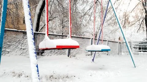 Closeup image of empty snow covered playground after blizzard. Blue and red Stock Photos