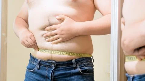 Closeup image of fat man measuring his fat tummy with yellow measuring tape Stock-Fotos