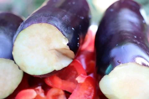 A closeup image featuring freshly chopped eggplants and red bell peppers inside Stock Photos