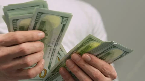 A CloseUp Image Featuring Hands Methodically Counting Stacks of Cash in a Stock Footage 317026187