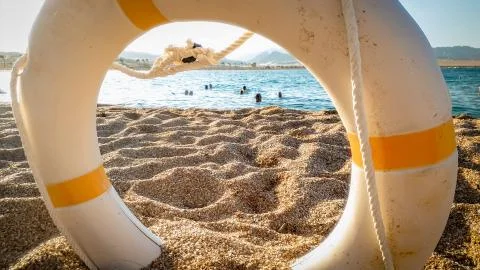 Closeup image of life saving ring to help people drowning in the sea lying on Stock Photos