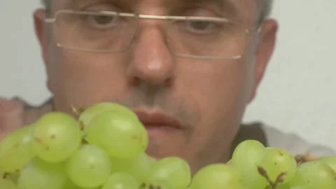 CloseUp Image of a Mans Hands Holding Fresh, Green Grapes Against a Colorful Видео 282017743