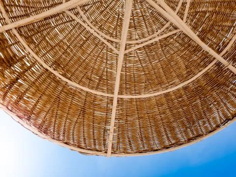 Closeup image of part of straw umbrella protecting from sun on the beach against Stock Photos