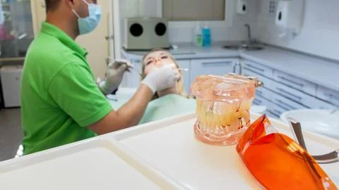 Closeup image of plastic teeth model and protective UV glasses on table in Stock Photos