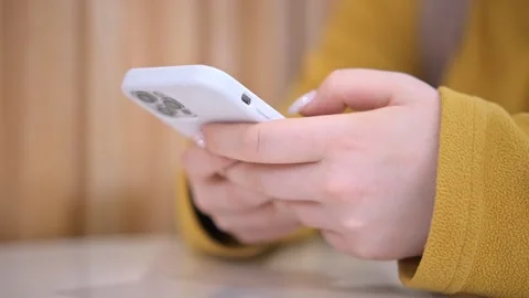 A closeup image showcases a persons hands using a smartphone with a white case Stock Footage 276533748
