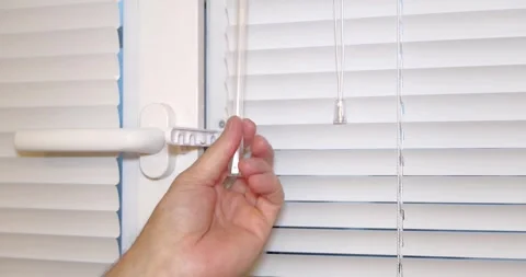 A closeup image showcasing a hand skillfully adjusting a window blind mechanism Stock Footage 315340030