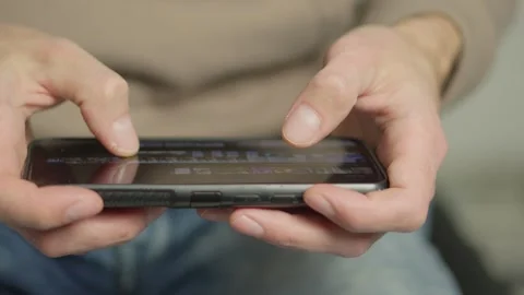 A closeup image shows hands using a smartphone, typing on the touchscreen. The Stock Footage 284710832