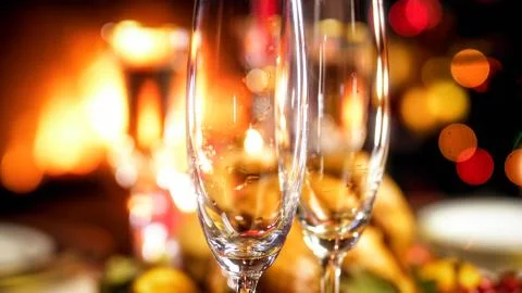 Closeup image of two empty champagne flutes against burning fireplace Stock-Fotos