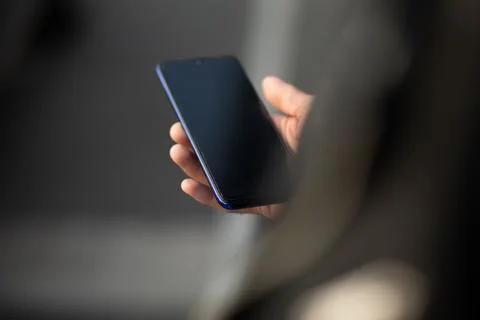 Closeup image of an unrecognizable young man holding mobile phone in hand, .. Stock Photos