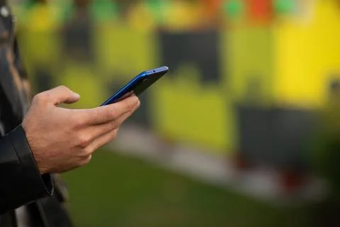 Closeup image of an unrecognizable young man holding mobile phone in hand, .. Stock Photos