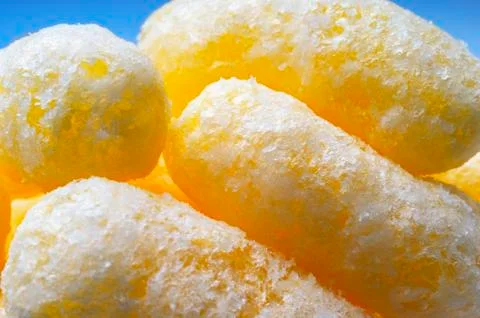 Closeup Image of Yellow Corn Puffs on Blue Background. Crunchy Flavored Puffe Stock Photos
