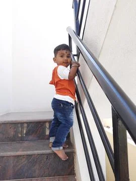 Closeup of Indian child going down the stairs of home with holding metal stan Stock Photos