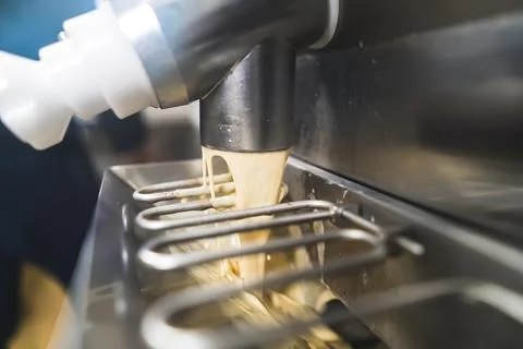 Closeup indoor shot of pasteurizer machine pouring ice cream into steel freezer Stock Photos