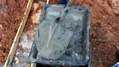 Closeup of a industry worker pouring liquid cement in a trench with a shovel. Stock Footage 109377460
