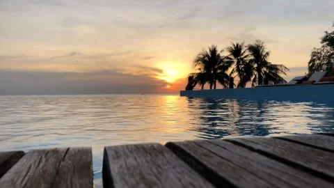 Closeup of infinity pool by the beach at sunset with palm trees Stock Footage 107576611